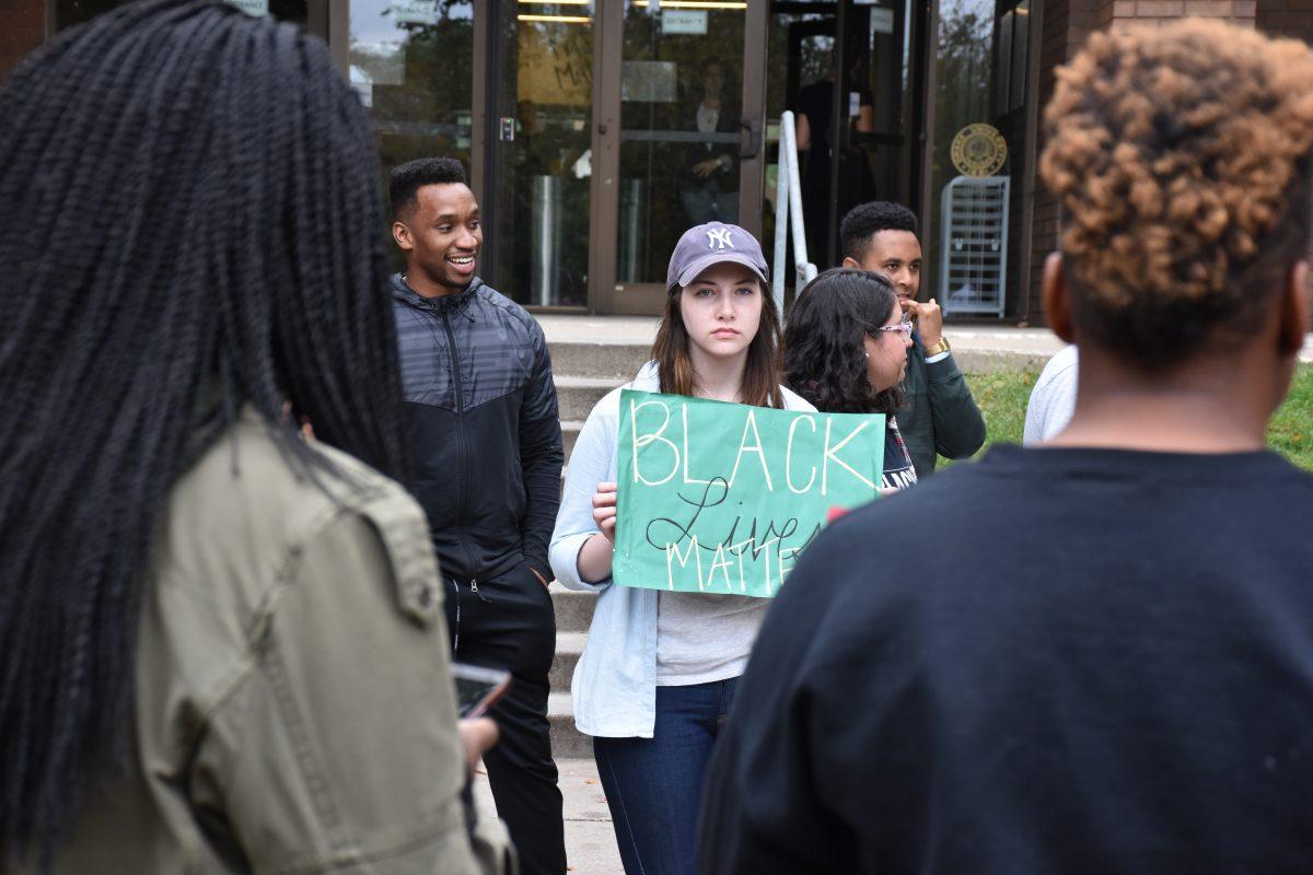 Student Senator Anna Gleason holds a sign reading "Black Lives Matter" while organizer of the protest Courtnei Caldwell gives a speech. 