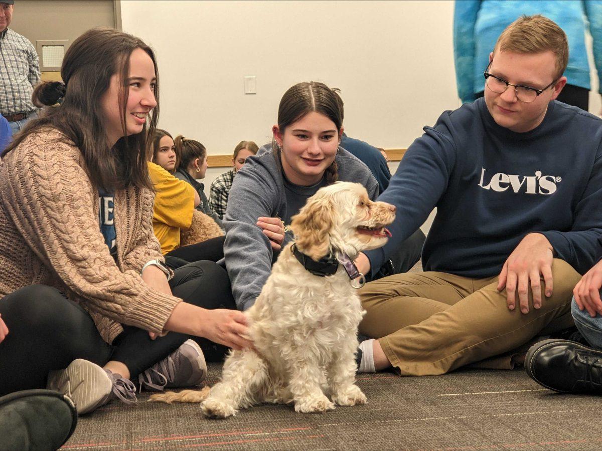 Drake University Students Sarah Tracy, Tegan Byford and Ethan Duesterhaus pet Grace the therapy dog during the finals destressing event in December. Therapy dogs will now come to Drake monthly. Photo by Maria Heath | Staff Writer