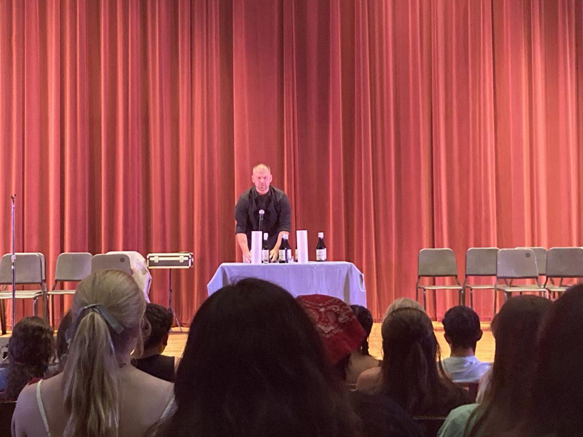 The multi-talented Josh McVicar performs a magic trick in front of Drake students, where he duplicates bottles of wine. Photo by Lily Wasserman. 