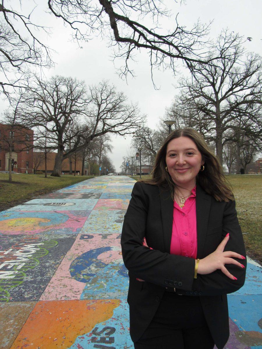 Katelyn Martin, Candidate for Vice President of Student Activities poses with Painted Street in the background.