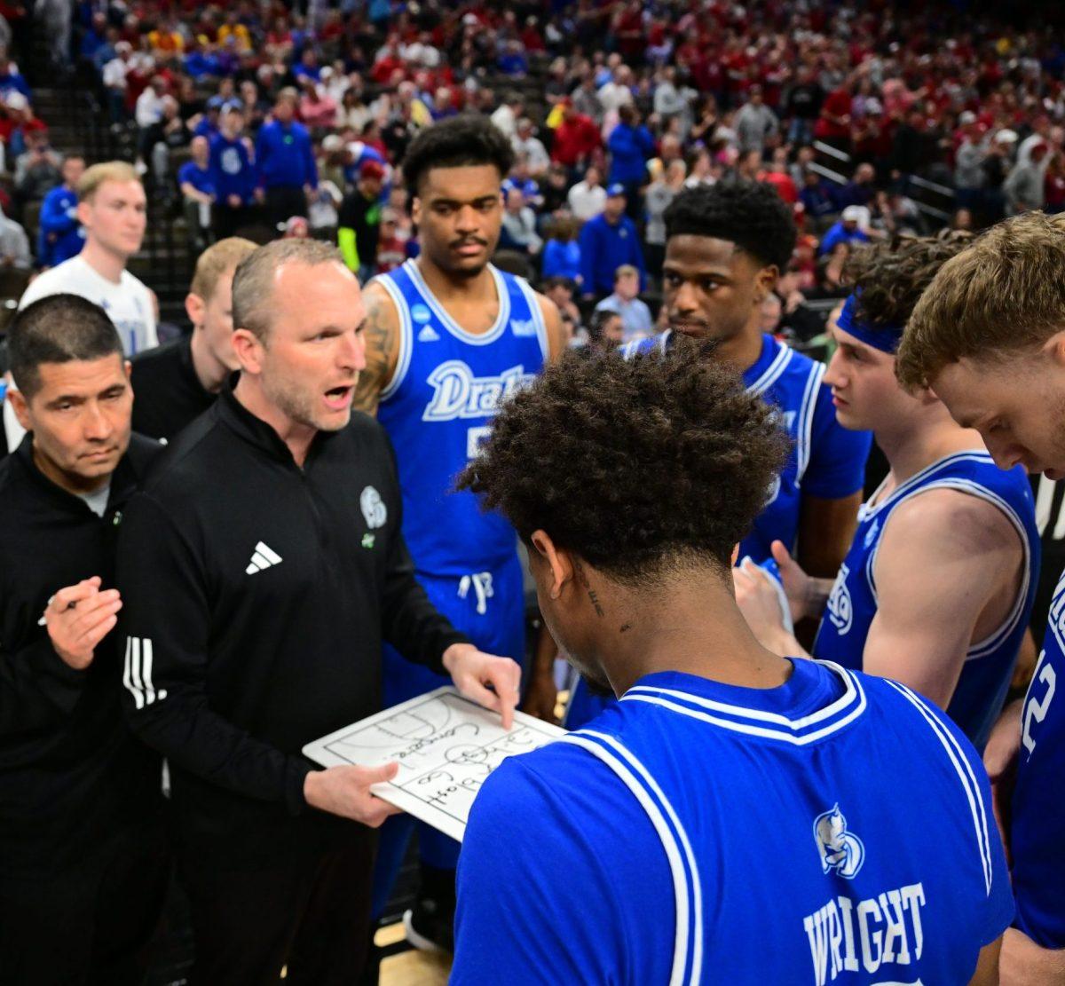 Former Drake men's basketball head coach, Darian DeVries talks to his players during a break in play