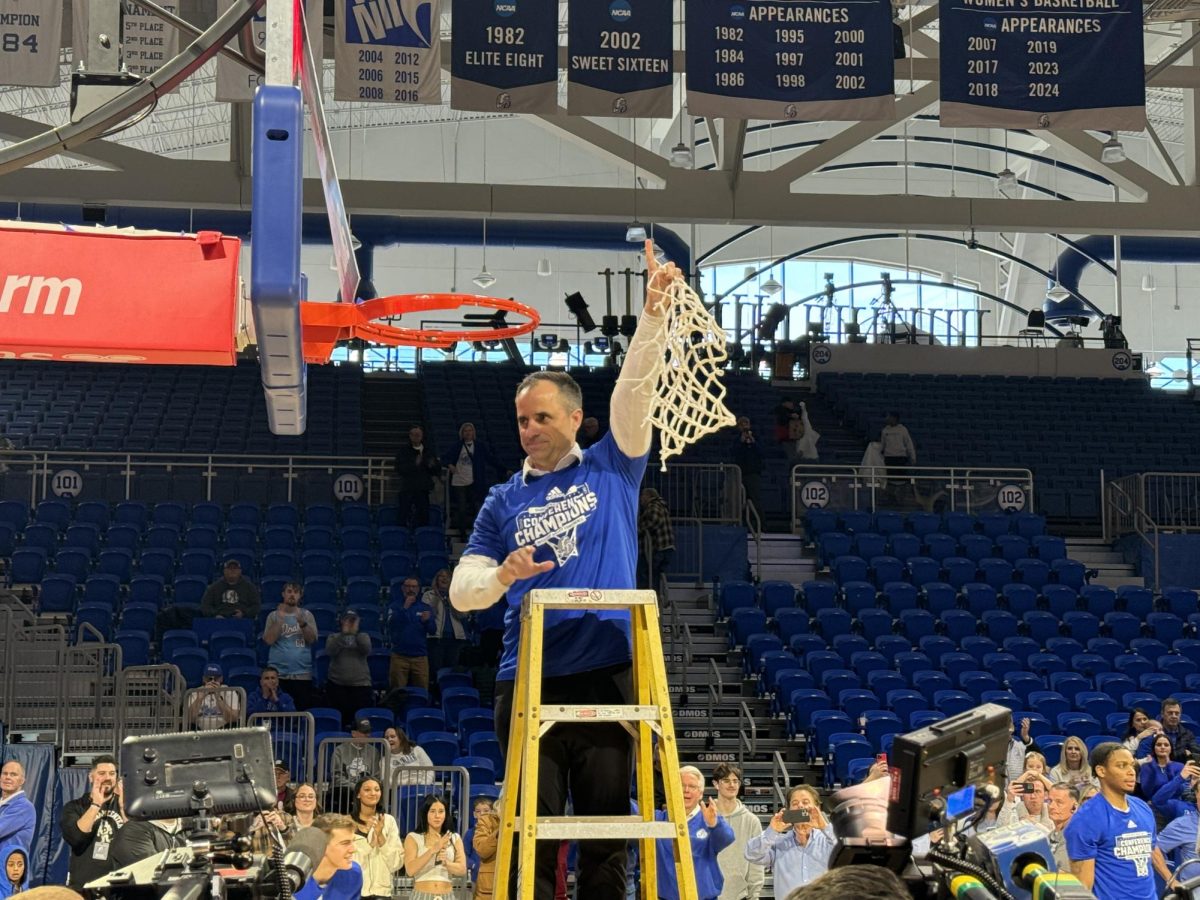 Men's basketball Head Coach Ben McCollum cuts down the net after the team’s last home game.  The women’s team will conclude gameplay on March 8 on the road.