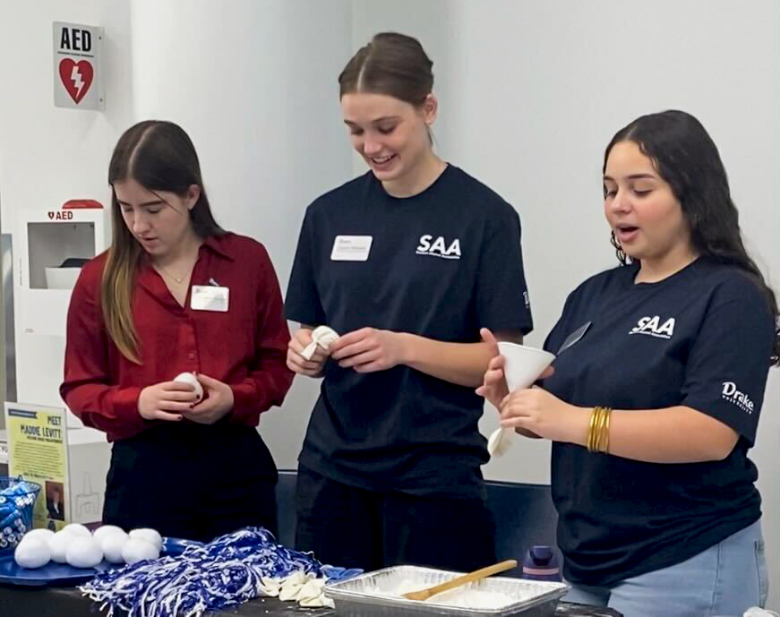 SAA members Elizabeth Mason, Charlie Mineart and María José Del Valle Laureano show attendees how to create stress balls with baking powder, conditioner and balloons at the Hubbelling event in the Olmsted Breezeway on Feb. 6.