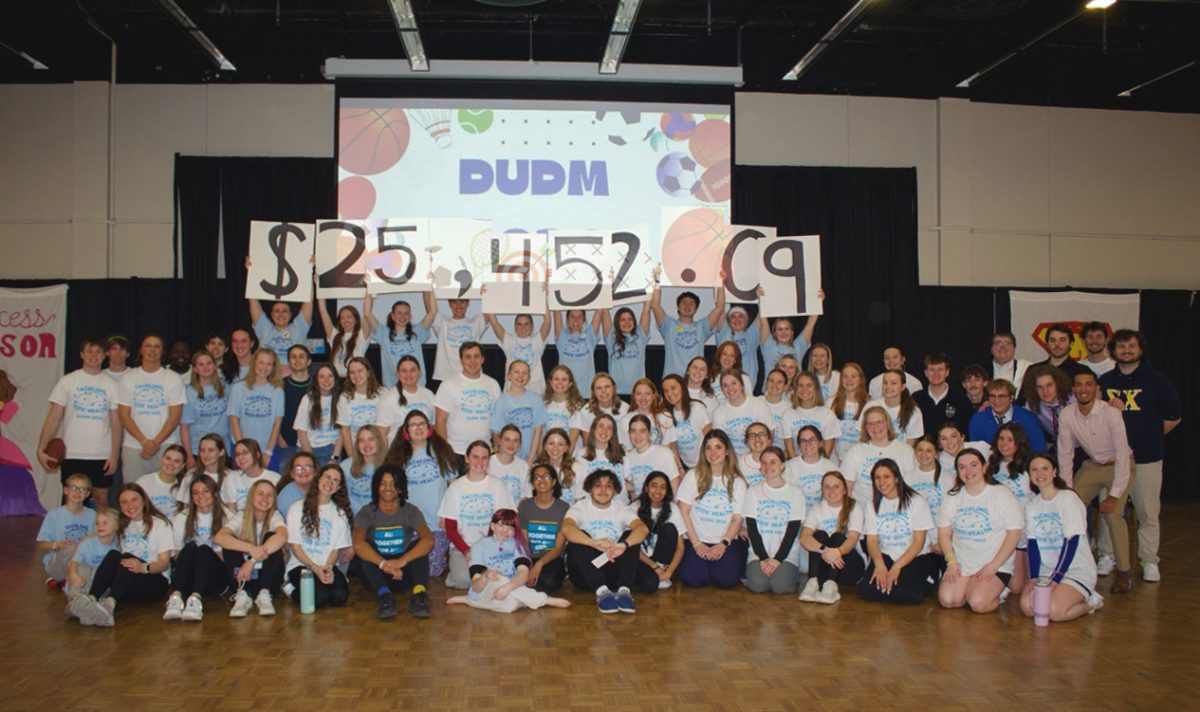 Attendees and miracle children sit together for a picture as Drake Dance Marathon morale captains hold up signs displaying the fundraising total Feb. 28 in Parents Hall. DUDM raised $25,452.09 from the Big Event and fundraising efforts throughout the year, a record for the organization. Photo courtesy of Elyse Landever