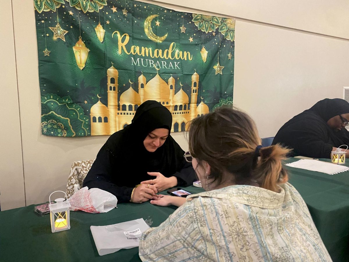  A henna artist paints a design on an attendee’s hand at Iftar Night March 3 in Parents Hall.  
